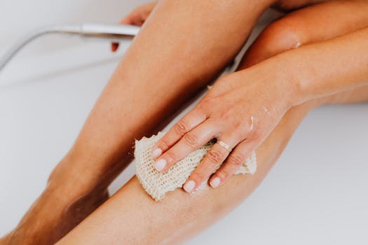 A close-up shot of a hand scrubbing a leg with a loofah, perfect for skincare and personal hygiene themes.