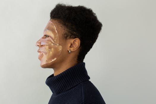 Studio portrait of a man wearing a facial mask, side profile with a light background.