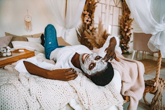 Woman enjoying a self-care day at home with a face mask, relaxing on her cozy bed.