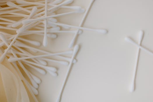 A detailed close-up of several cotton swabs scattered across a smooth, neutral surface, emphasizing cleanliness and hygiene.