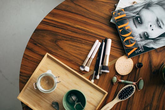 Stylish flatlay featuring makeup brushes, a Vogue magazine, and a coffee cup on a wooden table.